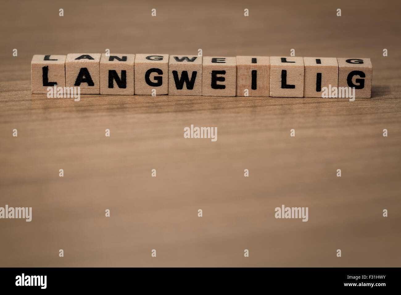 Langweilig (german Boring) written in wooden cubes on a desk Stock Photo