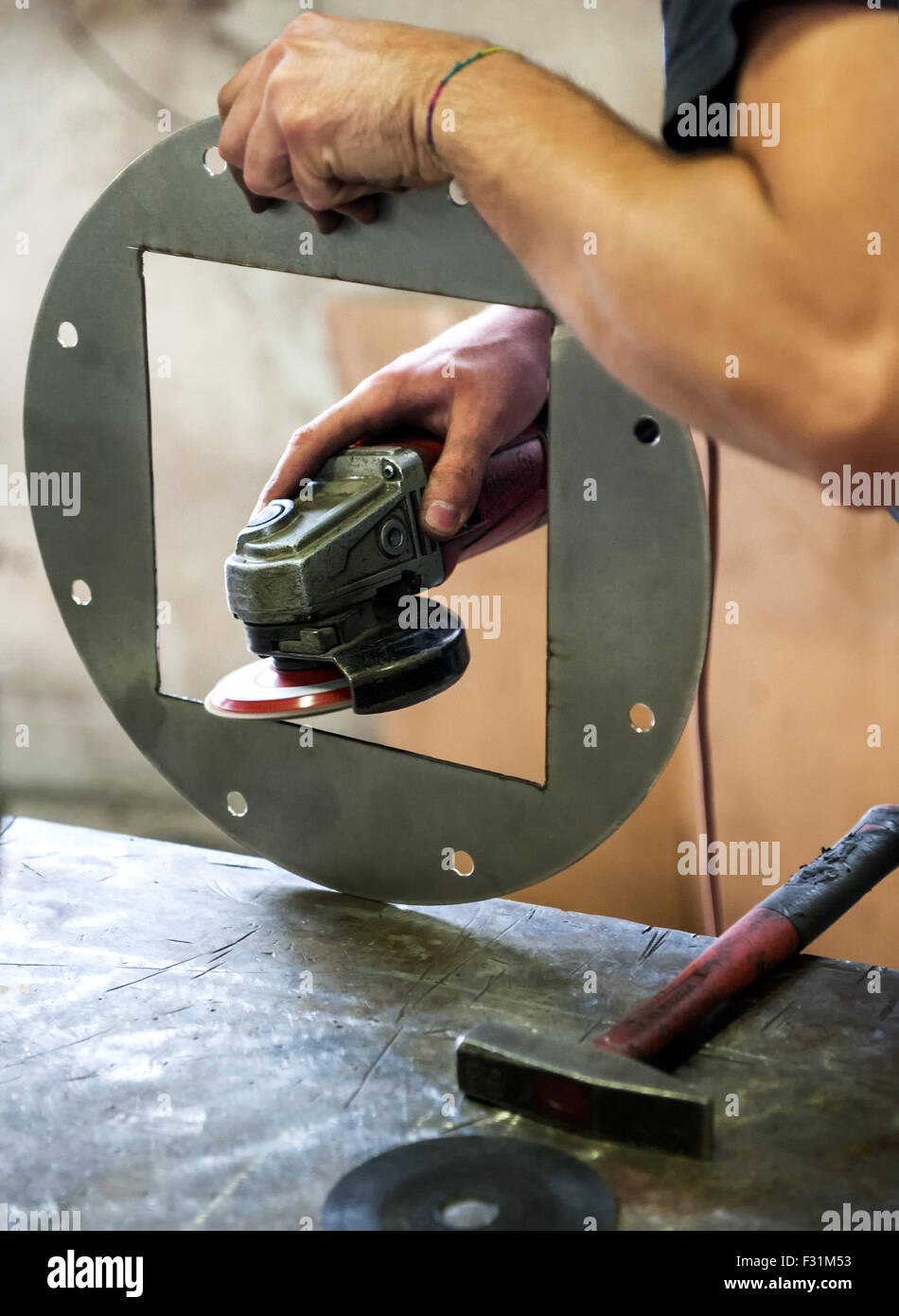 Metalworker sanding a metal component with a disc sander Stock Photo