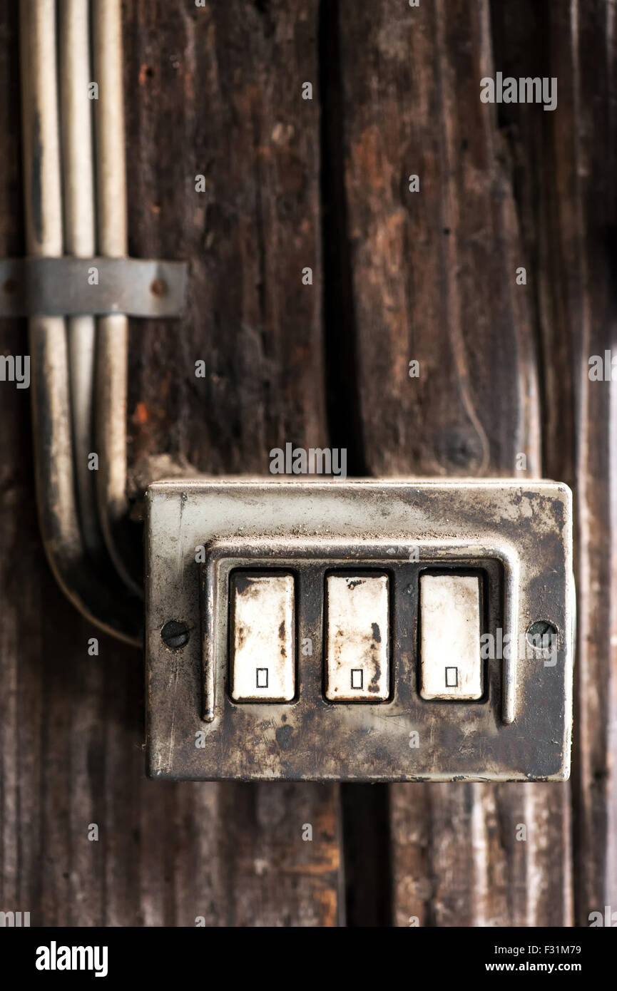 Row of three grungy electrical switches and wiring covered in grime and dirt Stock Photo