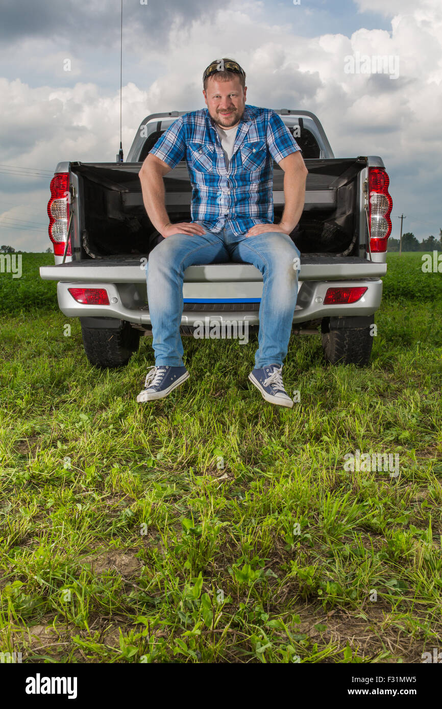 Solid man sitting on car trunk on natural background Stock Photo - Alamy