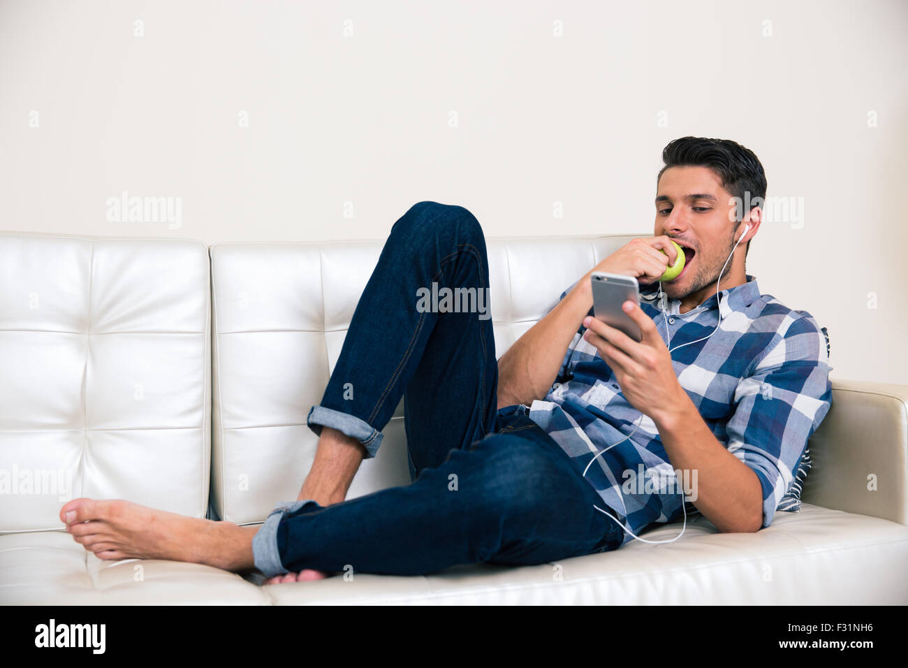 Man lying on sofa eating apple hi-res stock photography and images - Alamy