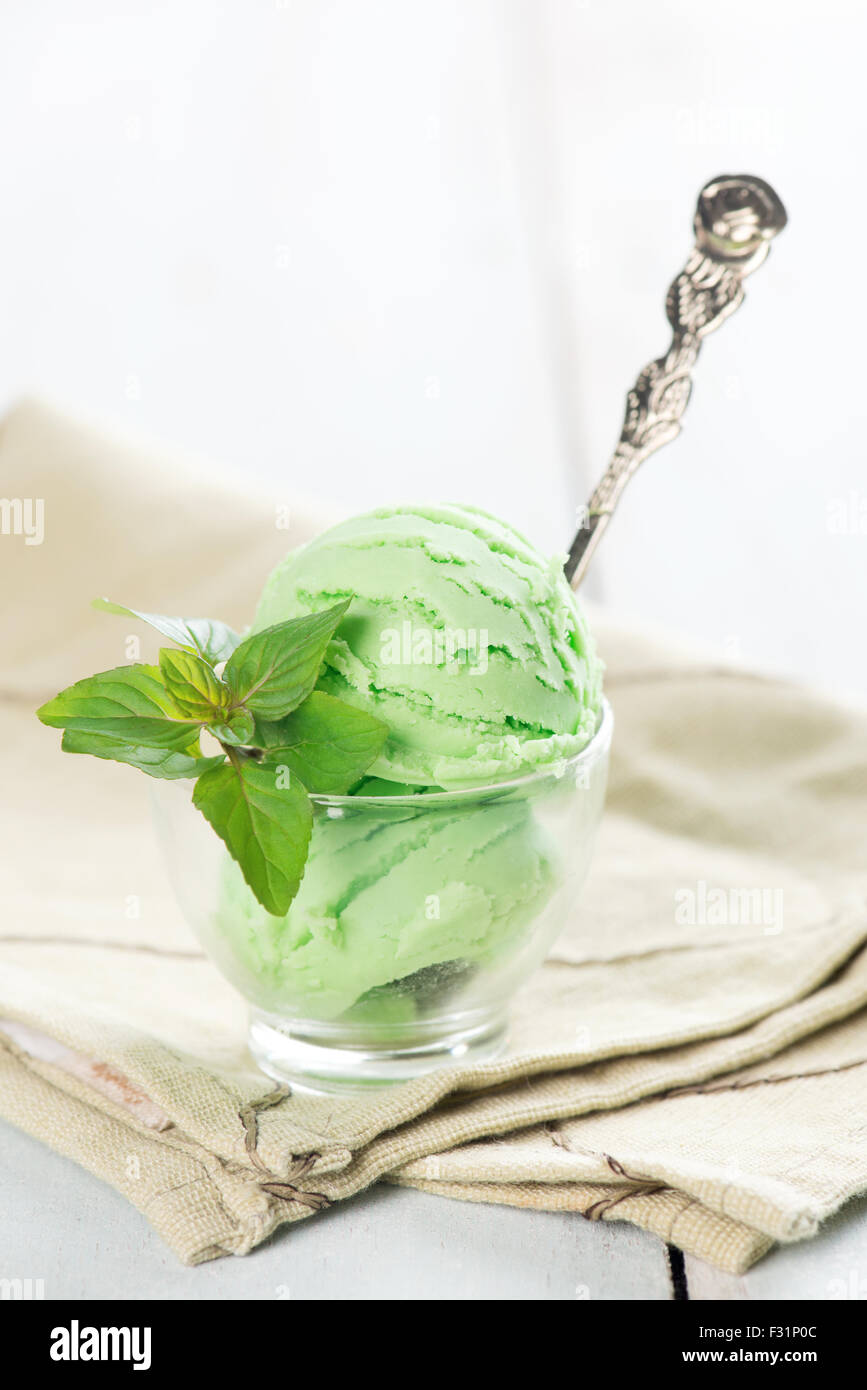Scoop of green tea ice cream in cup on wooden vintage background Stock
