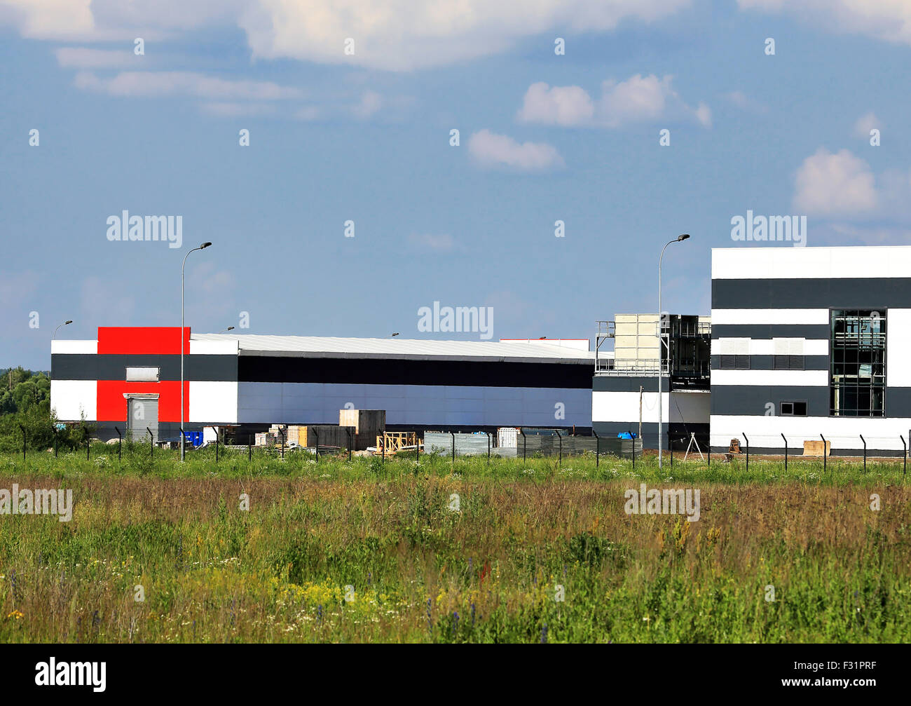 Large industrial facility with  the stock of the construction equipment nearby Stock Photo