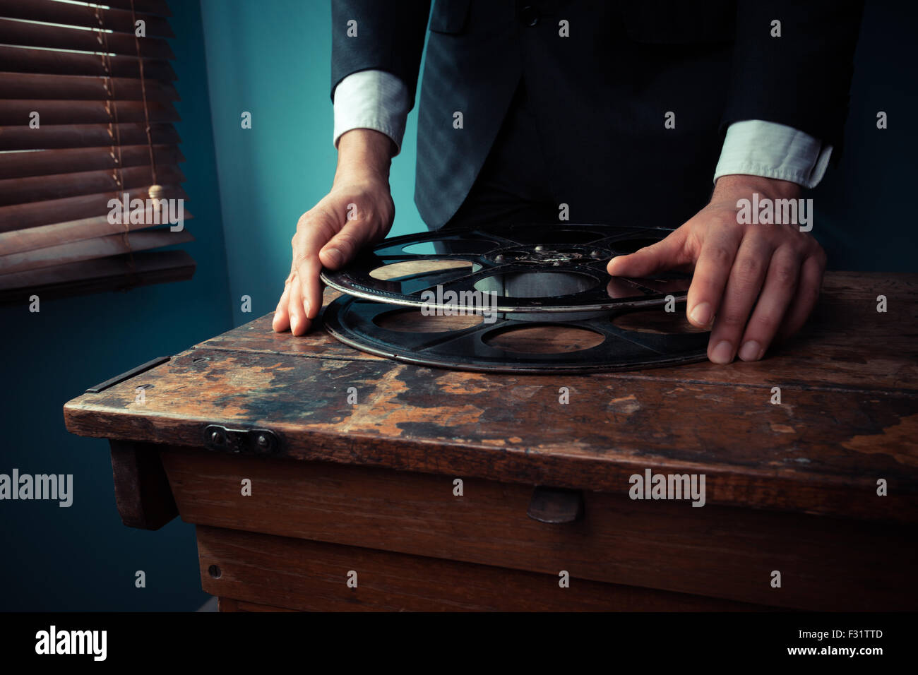 Film producer is handling a film reel in a projection room by the window Stock Photo