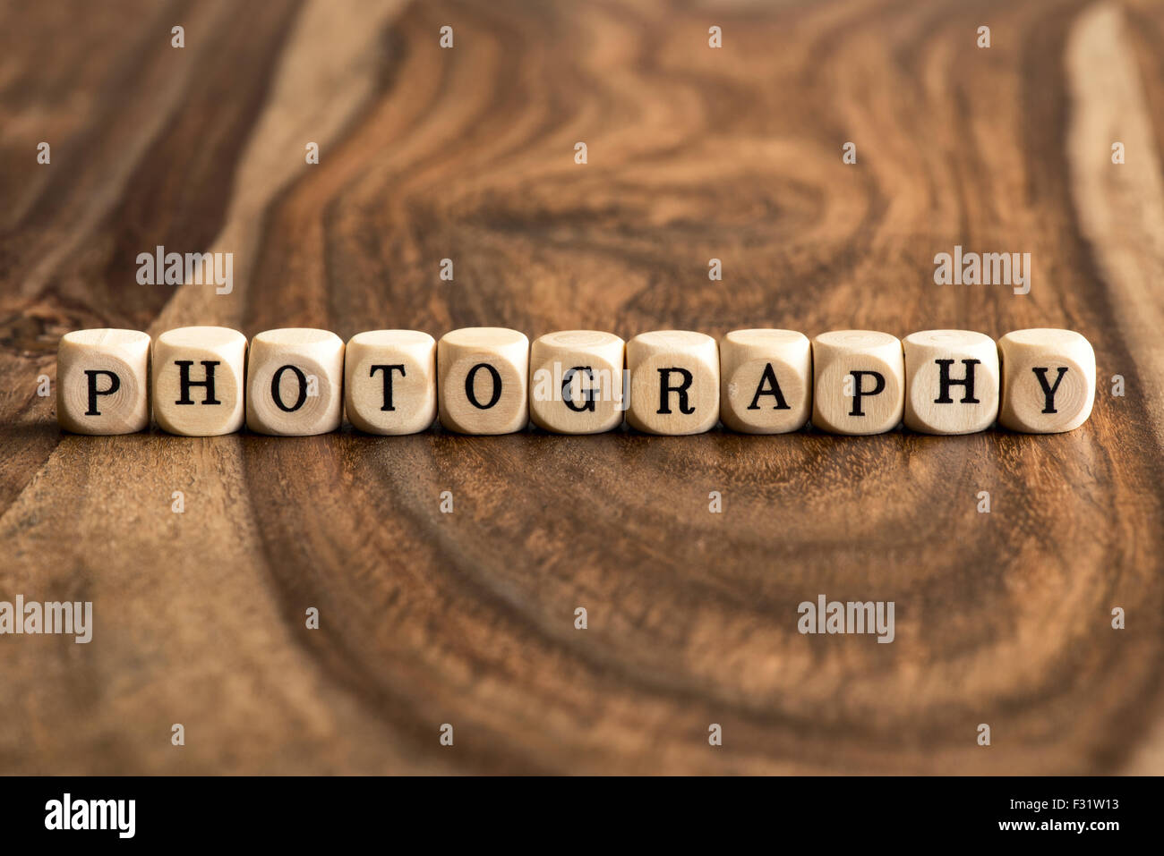 Word PHOTOGRAPHY made with block wooden letters over the wooden board surface Stock Photo