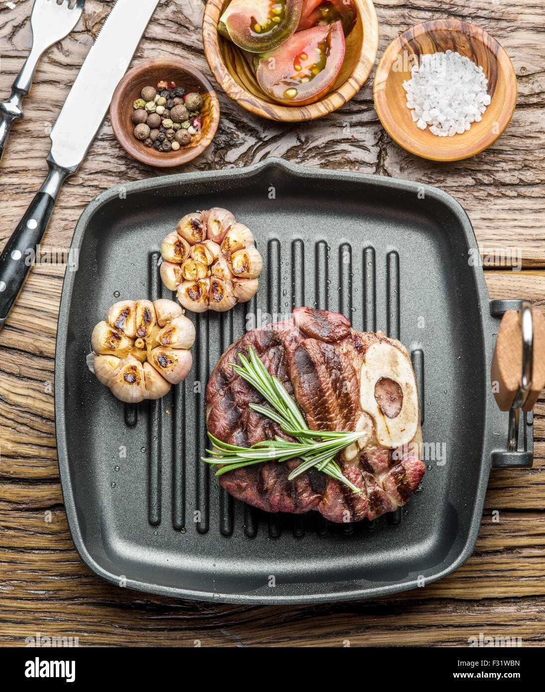 Beef steak with spices on pan on wooden table. Stock Photo