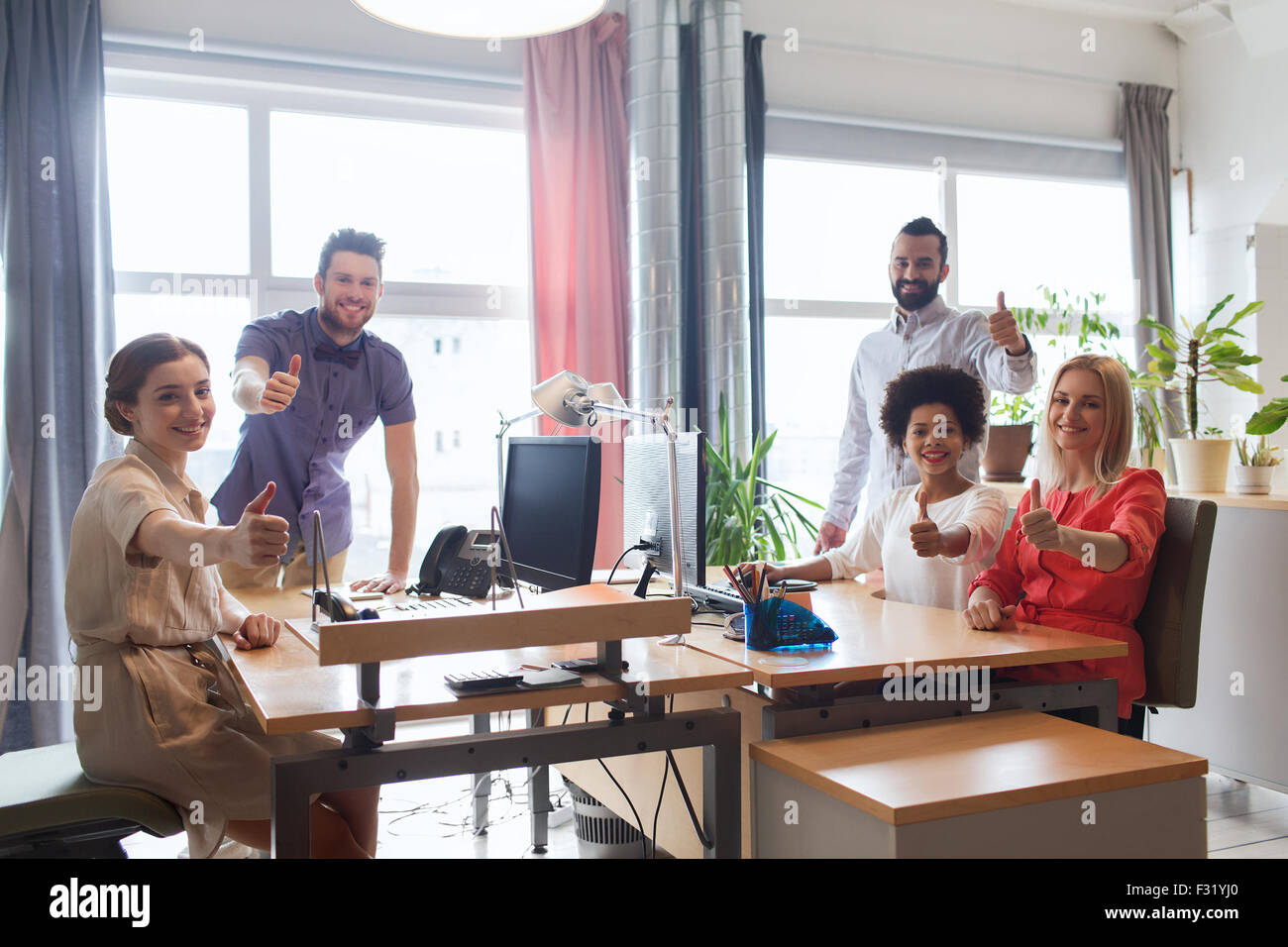 happy creative team showing thumbs up in office Stock Photo - Alamy