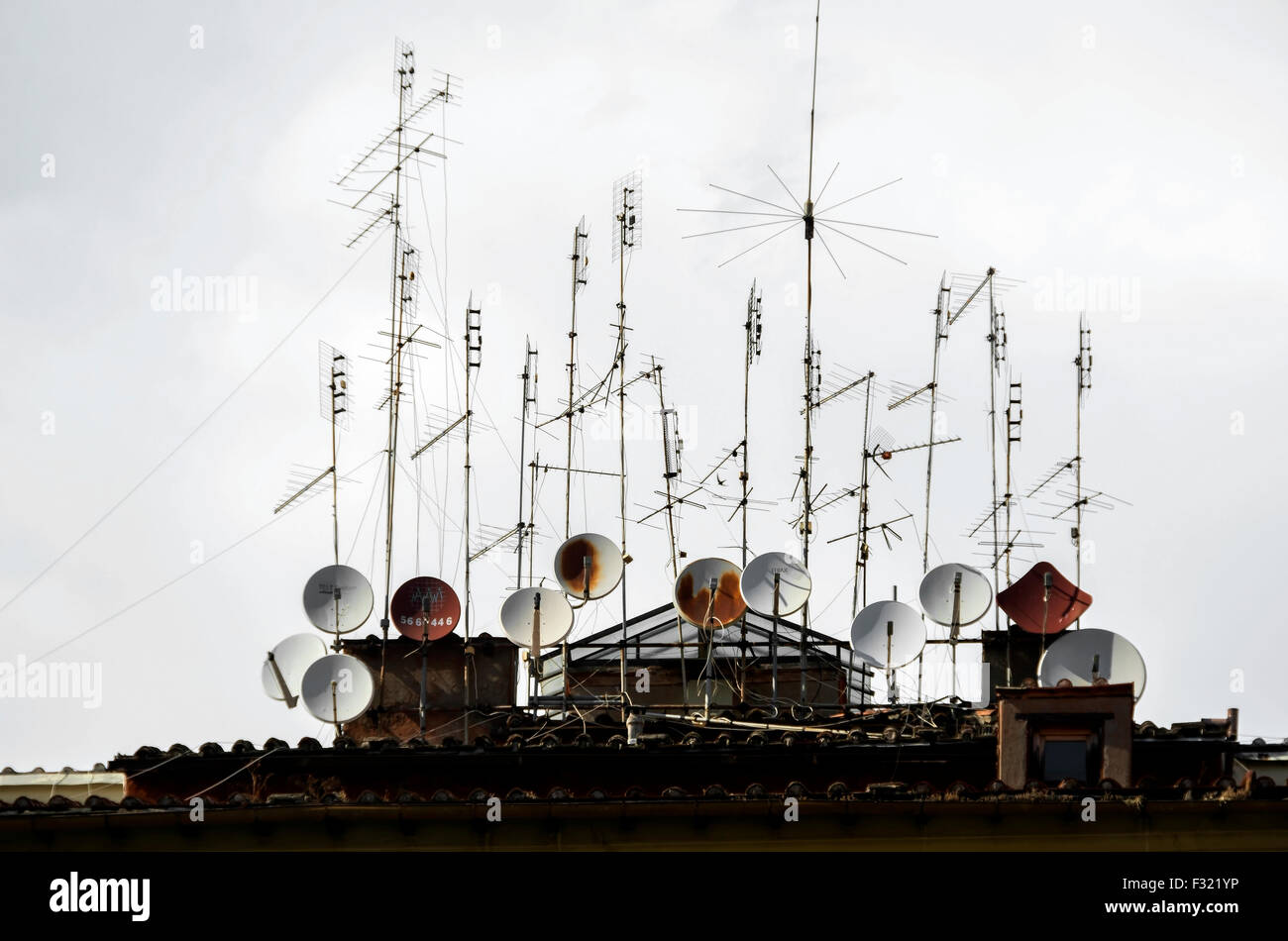 Multiple satellite dishes and television aerials on top of an apartment