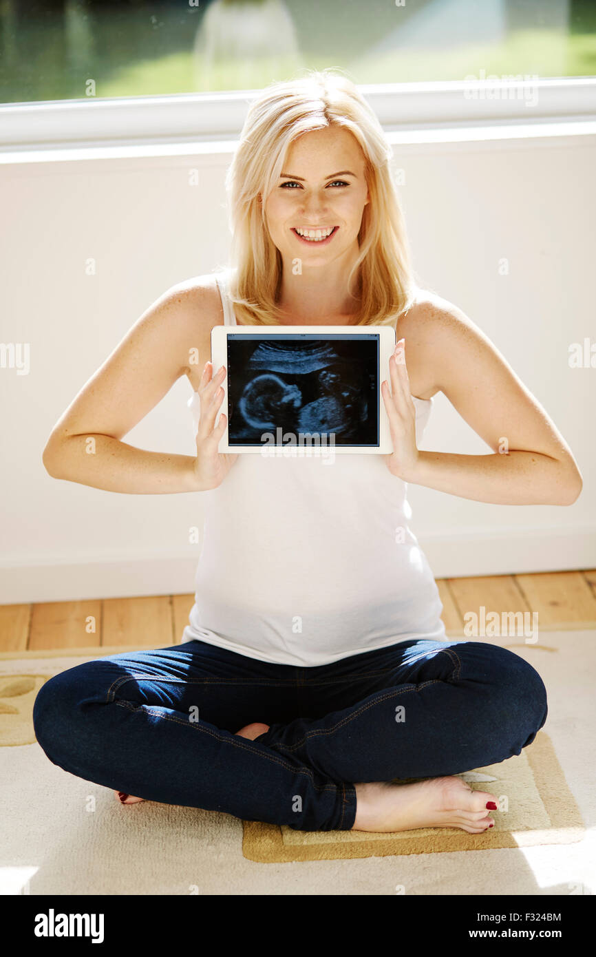Pregnant woman holding picture of baby scan Stock Photo