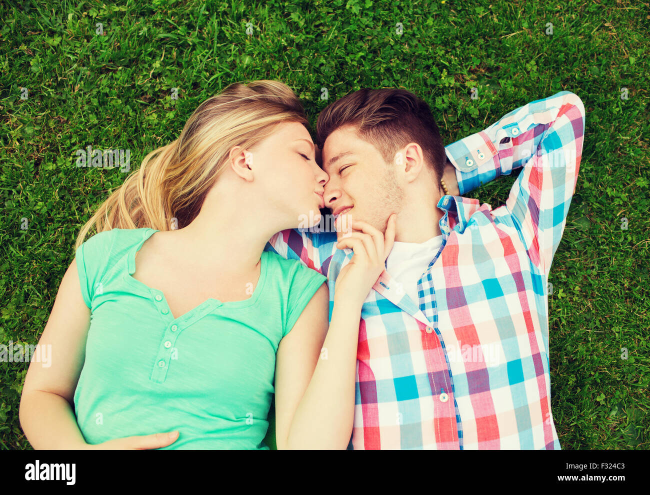 smiling couple lying on grass and kissing in park Stock Photo - Alamy