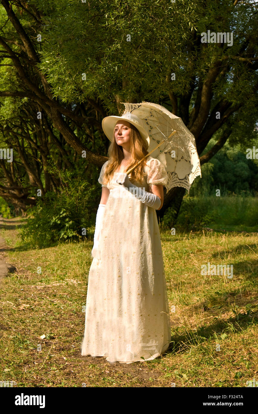Young lady in white historical dress with white umbrella standing in ...