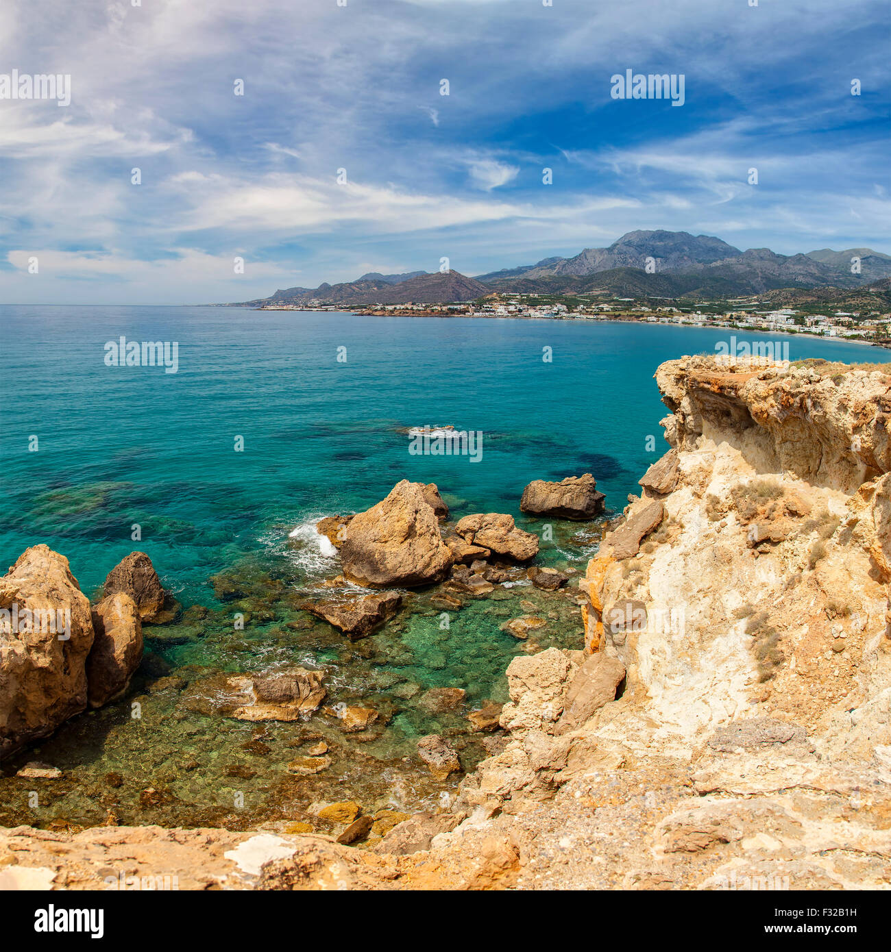 Rocky seaside landscape on Crete, Greece. Makrigialos village in the background. Stock Photo