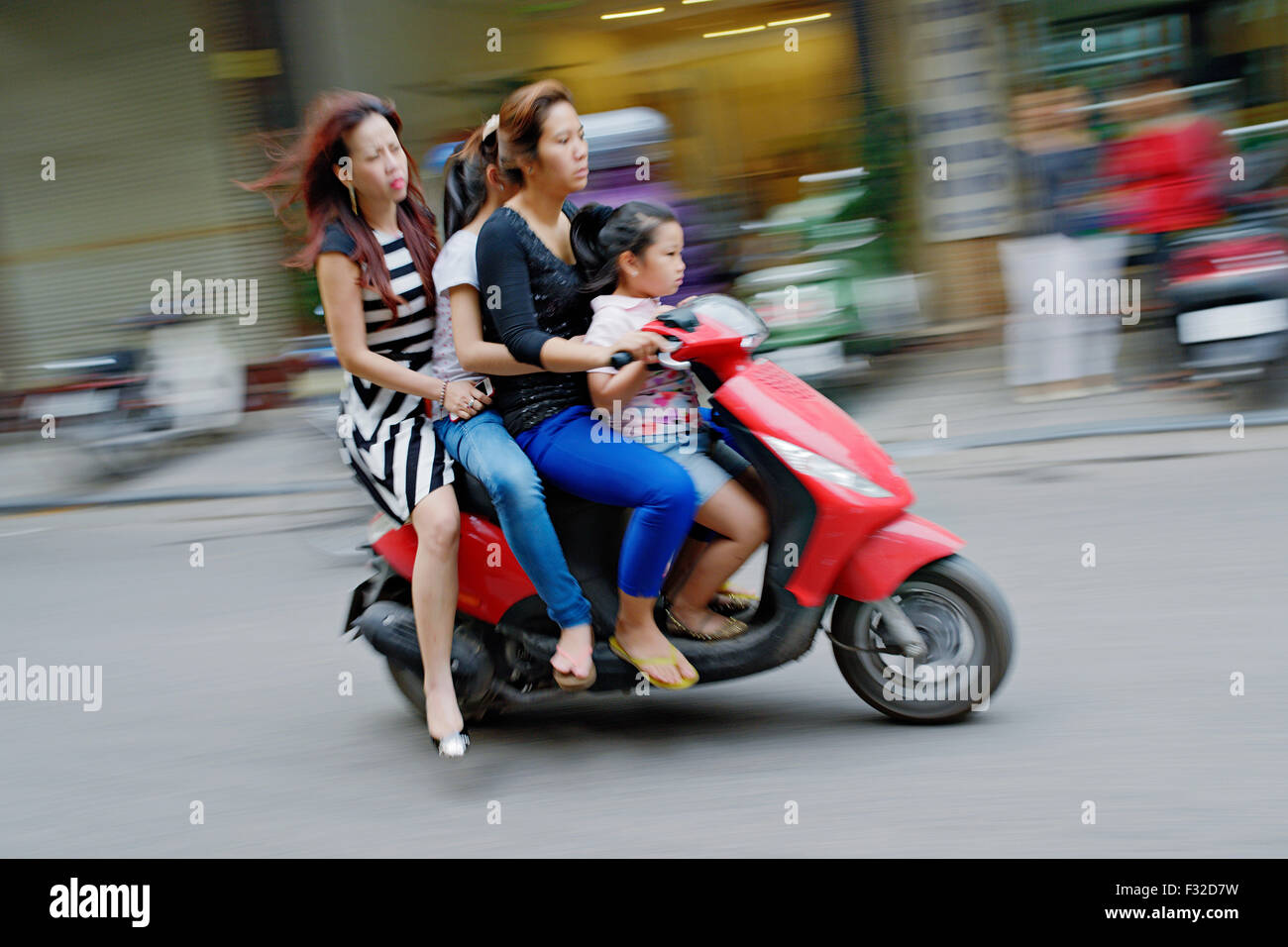 Mopeds and motorbikes are everywhere in Hanoi, Vietnam. It's not rare to see a whole family riding on only one scooter. Stock Photo