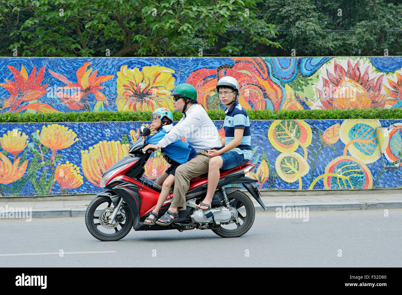 Mopeds and motorbikes are everywhere in Hanoi, Vietnam. It's not rare to see a whole family riding on only one scooter. Stock Photo