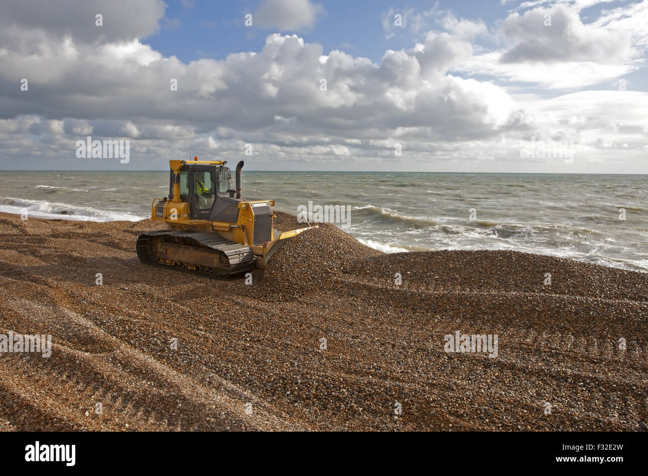 Bulldozer recycling and regrading shingle for beach defences, Hythe ...