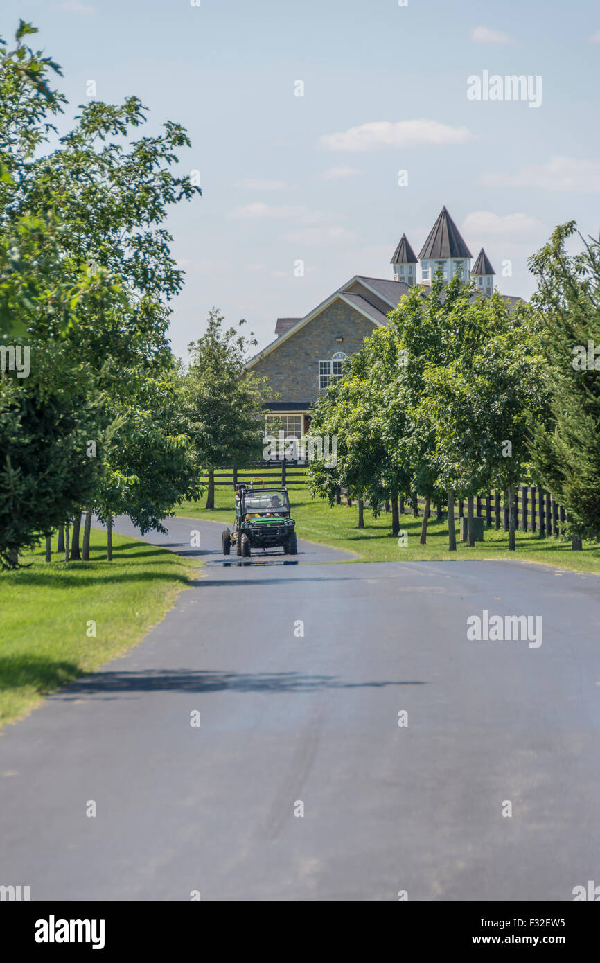 Entrance road with maintenance vehicle to thoroughbred horse barn in Lexington Kentucky USA Stock Photo
