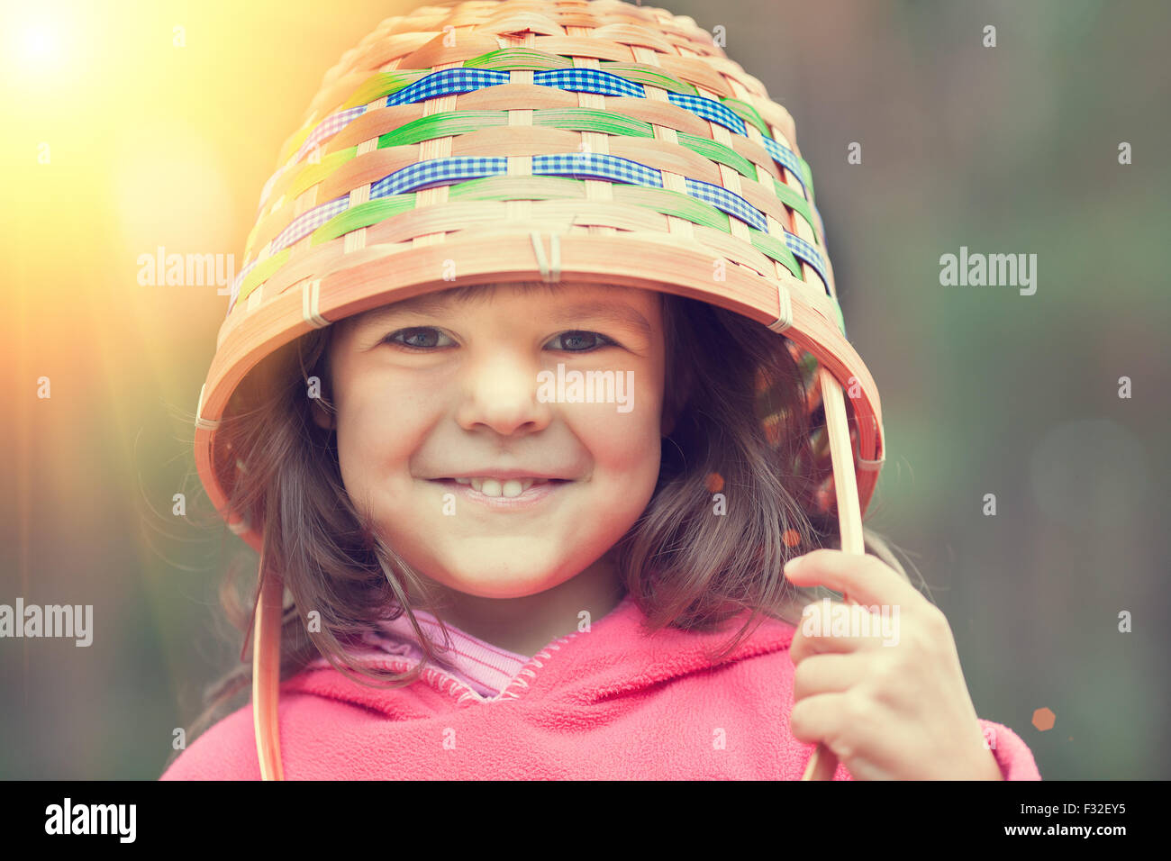 Happy smiling little girl wearing picnic basket outdoors Stock Photo