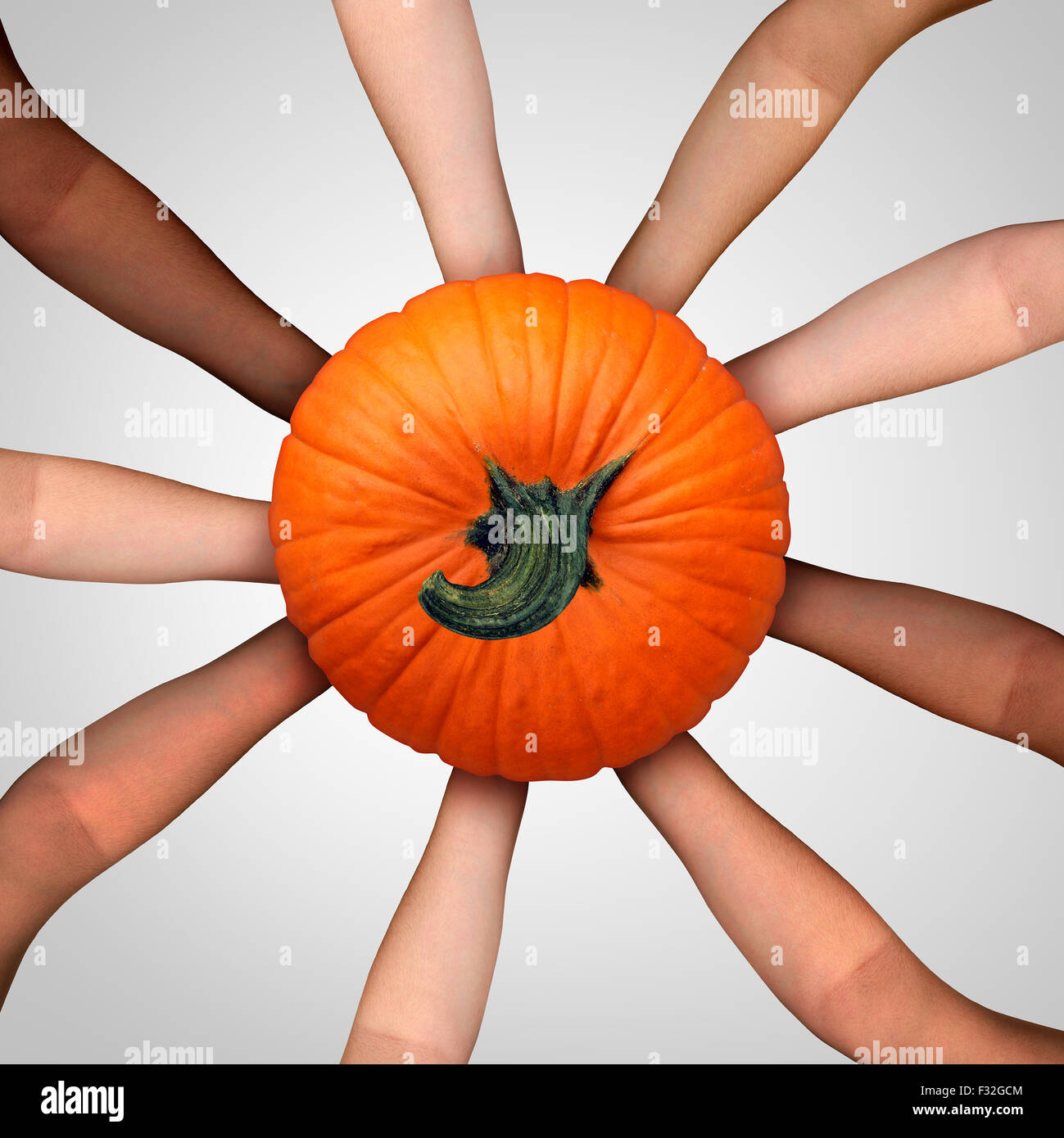 Community harvest concept as an ethnicaly diverse multicultural group of people holding a ripe pumpkin as a social cooperation symbol for thanksgiving dasy celebration and autumn harvesting time or Halloween season. Stock Photo