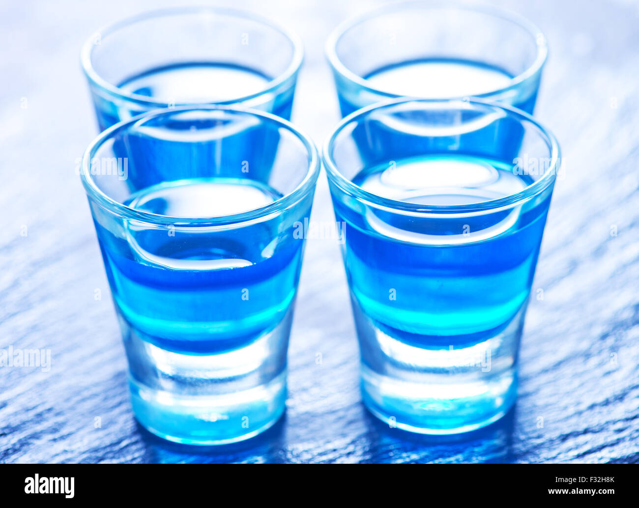 blue alcoholic drink into small glasses on a table Stock Photo - Alamy