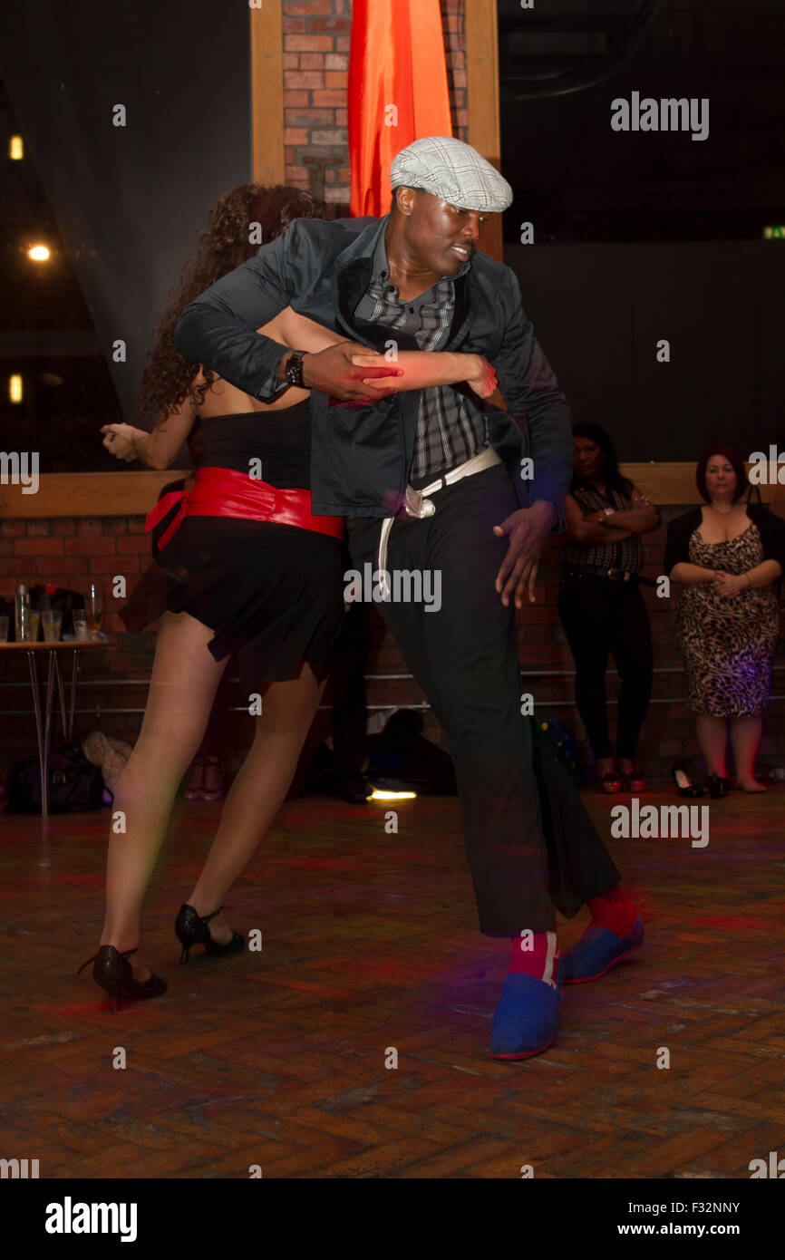 Semba dance show in a club, young couple dancing salsa. Kizomba dance performance. Smiling black man leading white woman Stock Photo