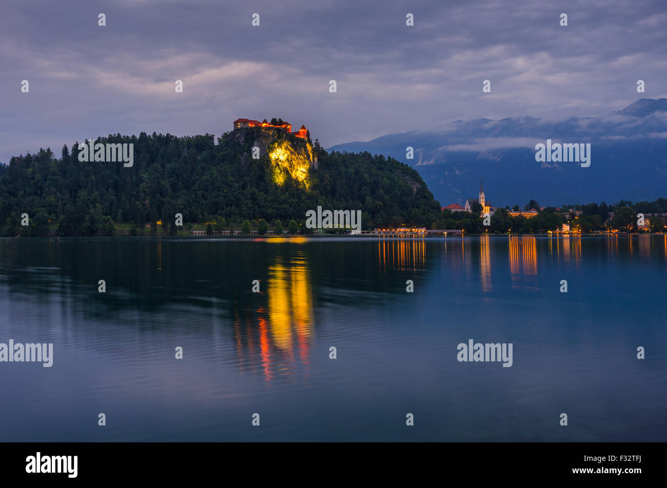 Illuminated Bled Castle at Bled Lake in Slovenia at Night Reflected on Water Surface Stock Photo