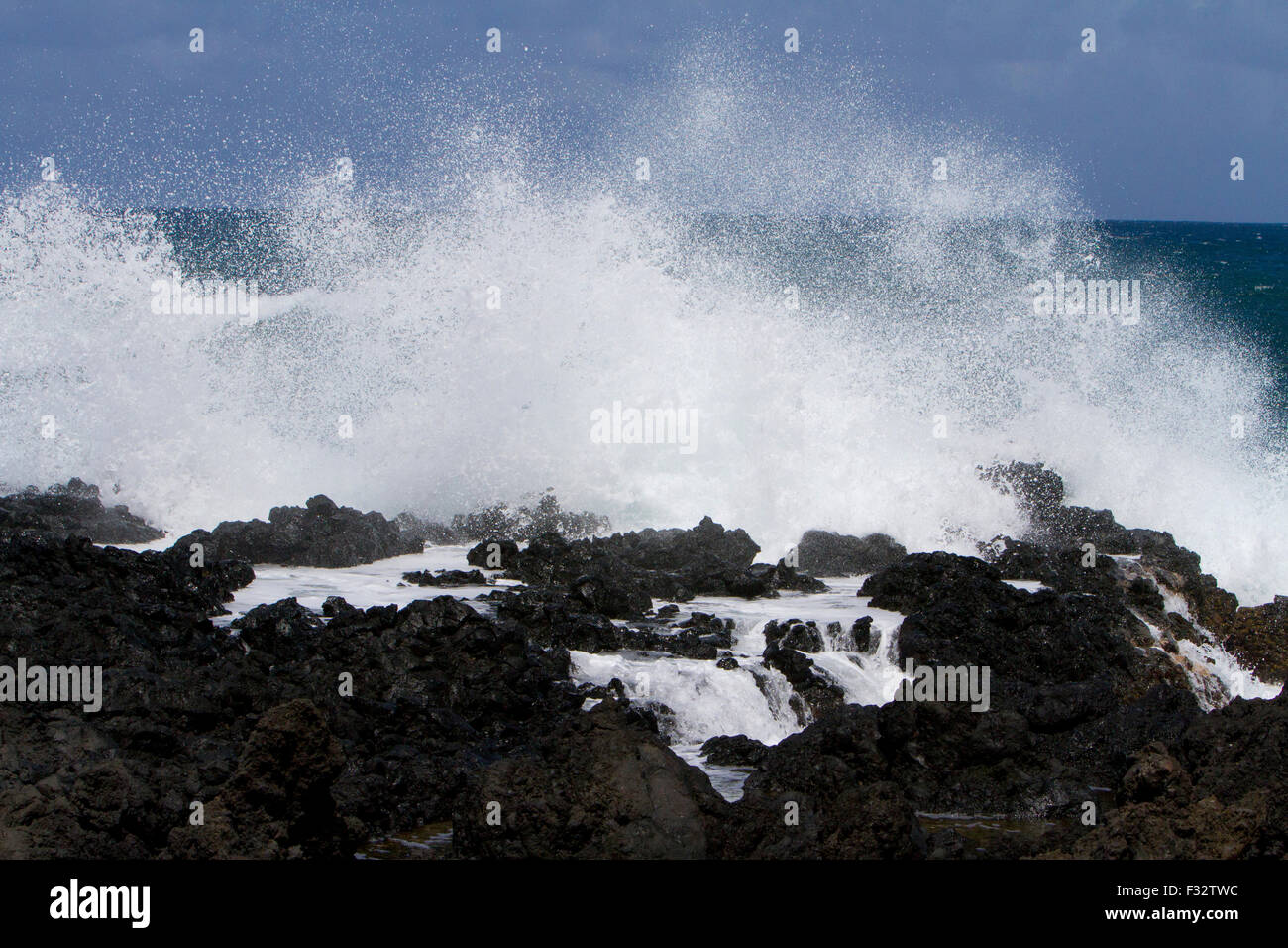 Waves crashing against rocks along the shoreline at Keanae Peninsula, just off Hana Highway, Maui, Hawaii in August Stock Photo