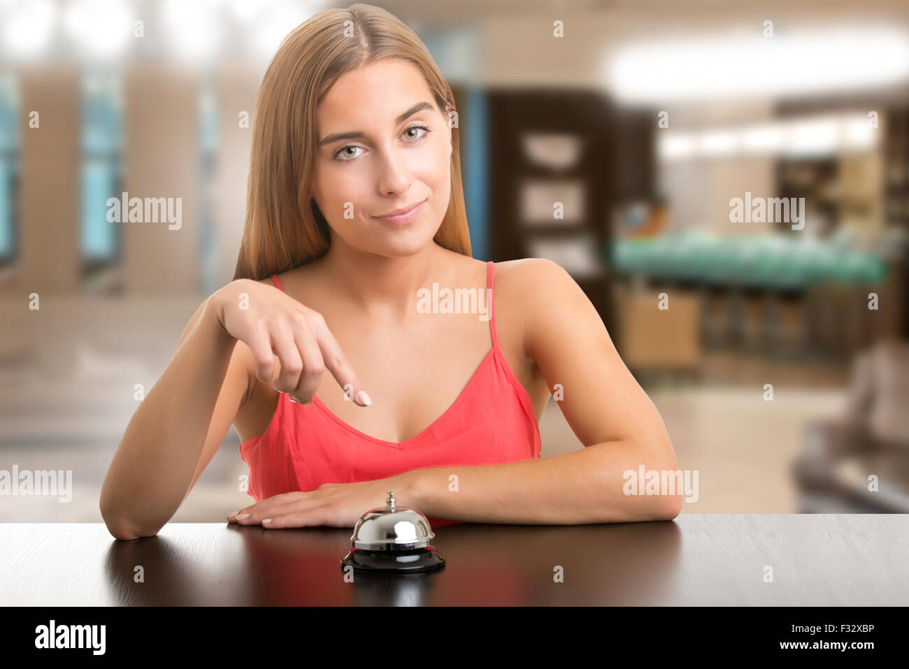 Woman about to ring a counter bell isolated in an hotel Stock Photo