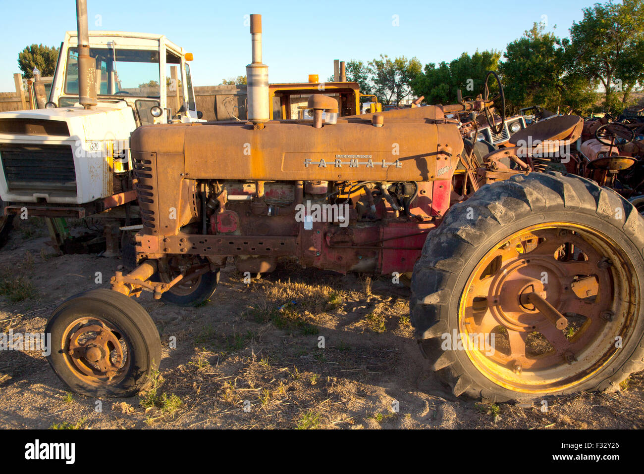 Rusted Farmall farm tractor in junkyard at sunset,US, 2015. Stock Photo