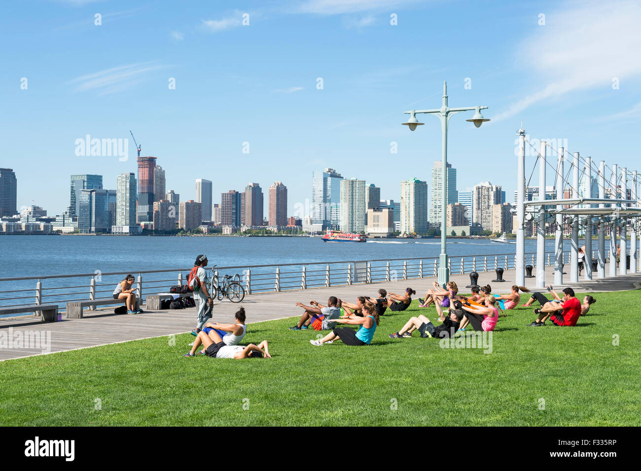 NEW YORK CITY, USA - AUGUST 29, 2015: Personal trainer leads group boot camp fitness class near the Hudson River. Stock Photo