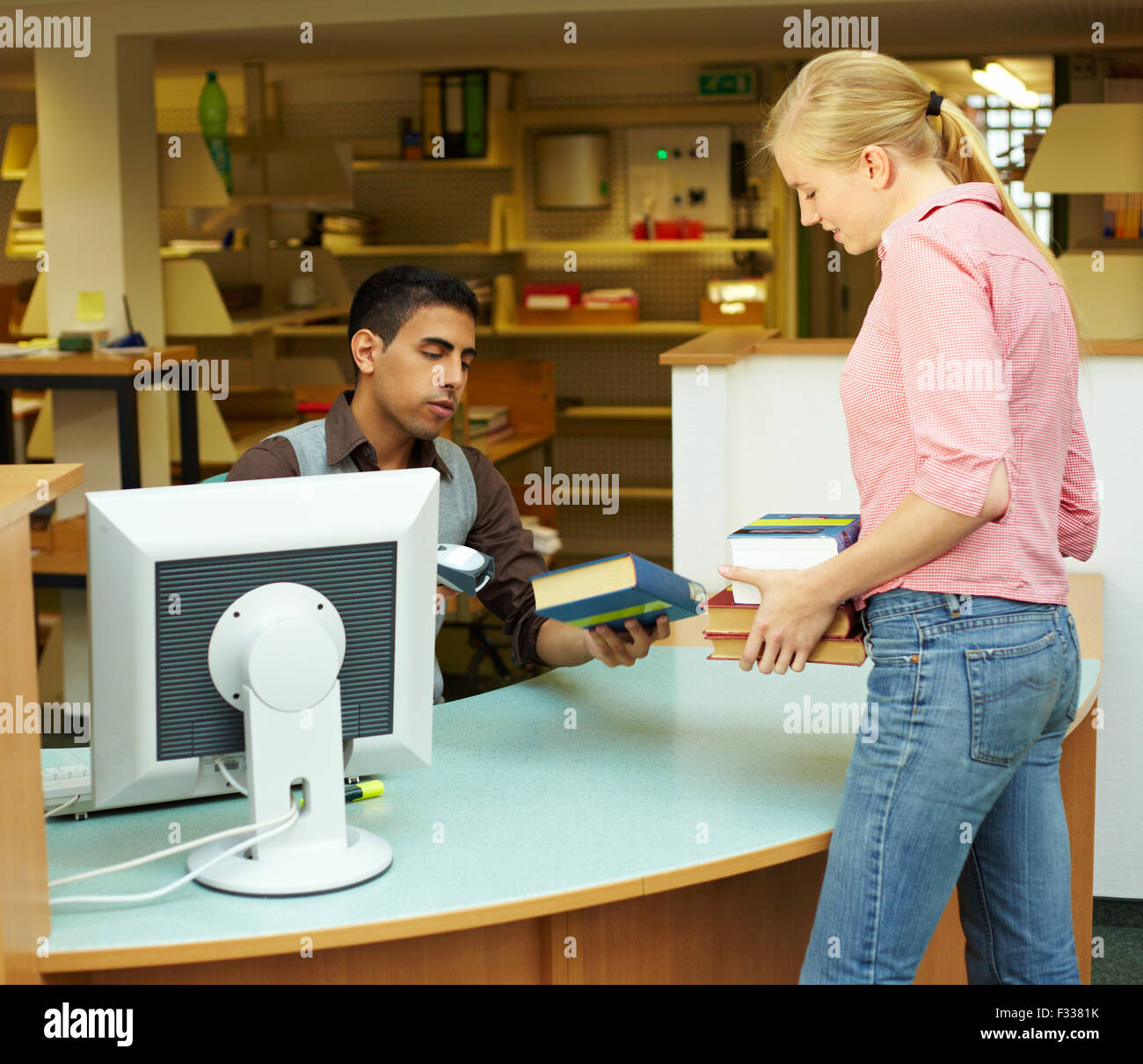 Employee scanning books in library at counter Stock Photo Alamy