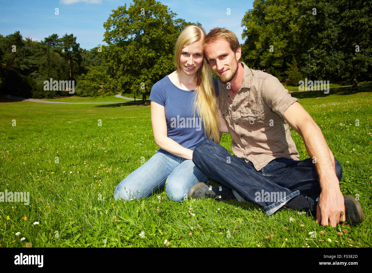 Young couple sitting outside in a park Stock Photo - Alamy