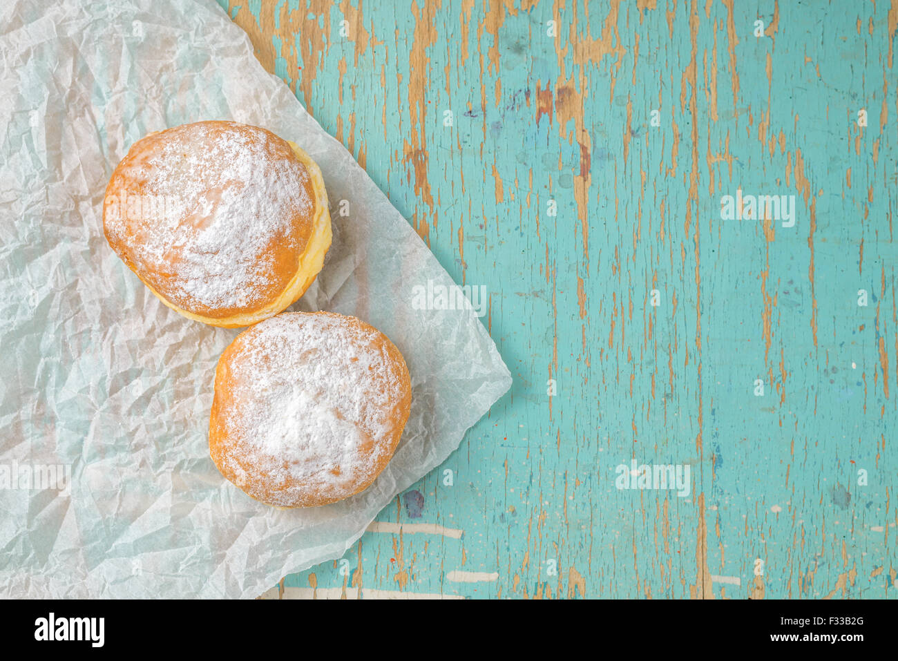 Sweet sugary donuts on rustic wooden kitchen table, top view of tasty bakery doughnuts in vintage retro toned overhead shot Stock Photo