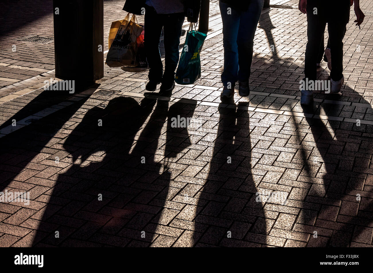 Pedestrians shoppers in Dublin, Ireland with plastic carrier shopping bags Stock Photo