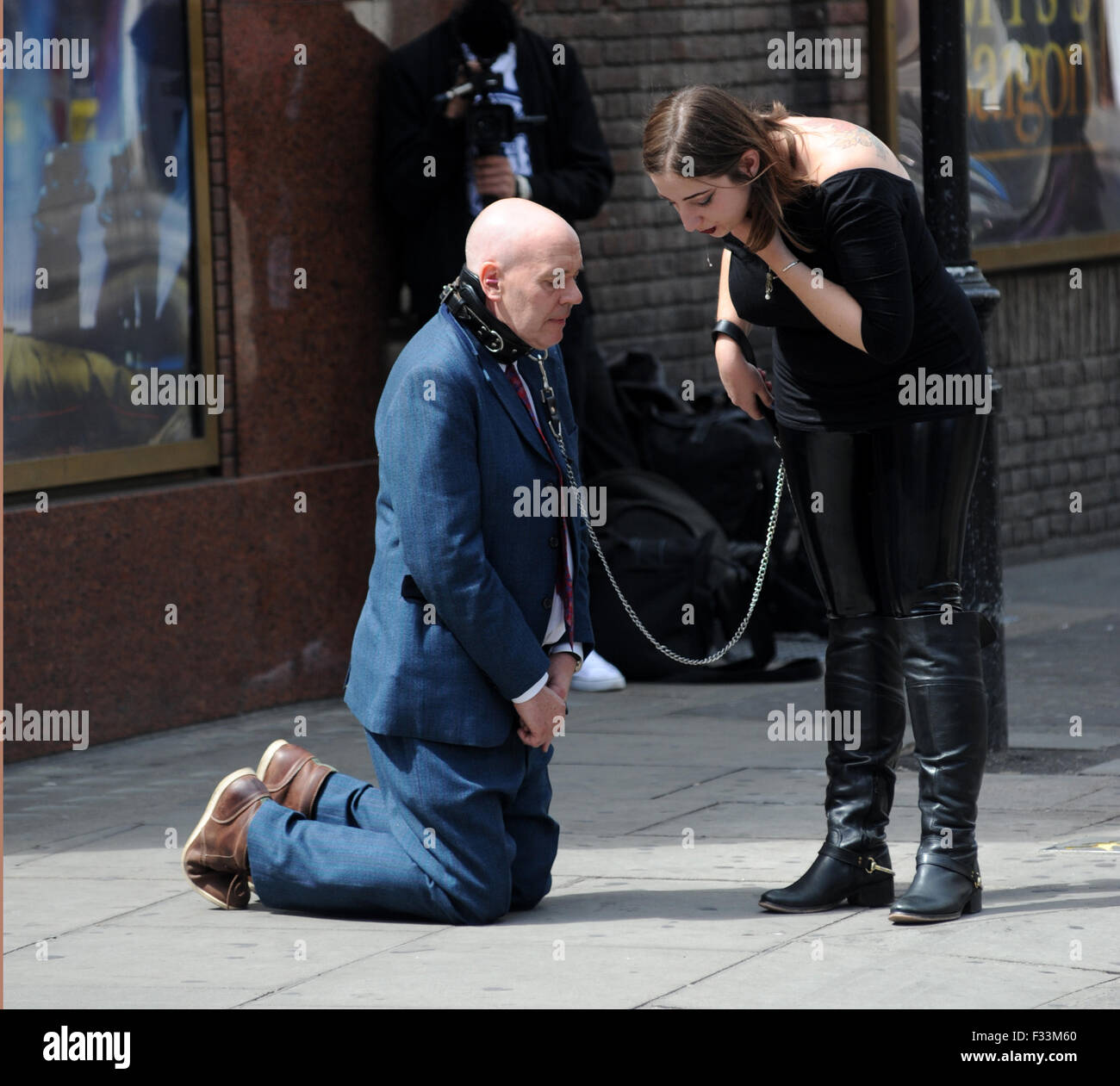 A man being publicly humiliated by a dominatrix in the streets of Soho,  where he was made to lick up her spit and had cigarettes stubbed out on his  tongue as he