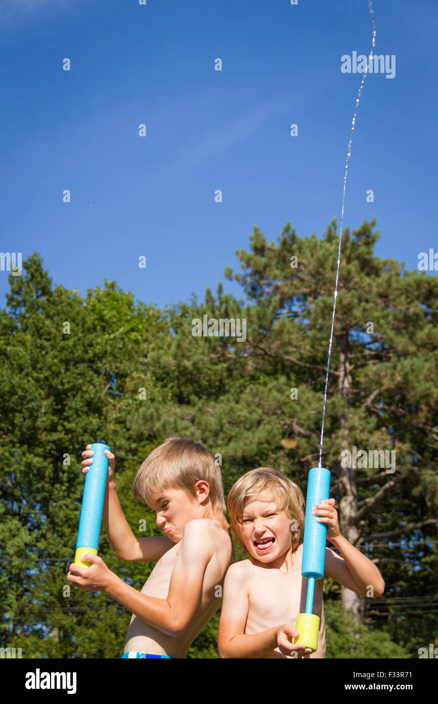 Two young boys outdoors playing with squirt toys. Stock Photo