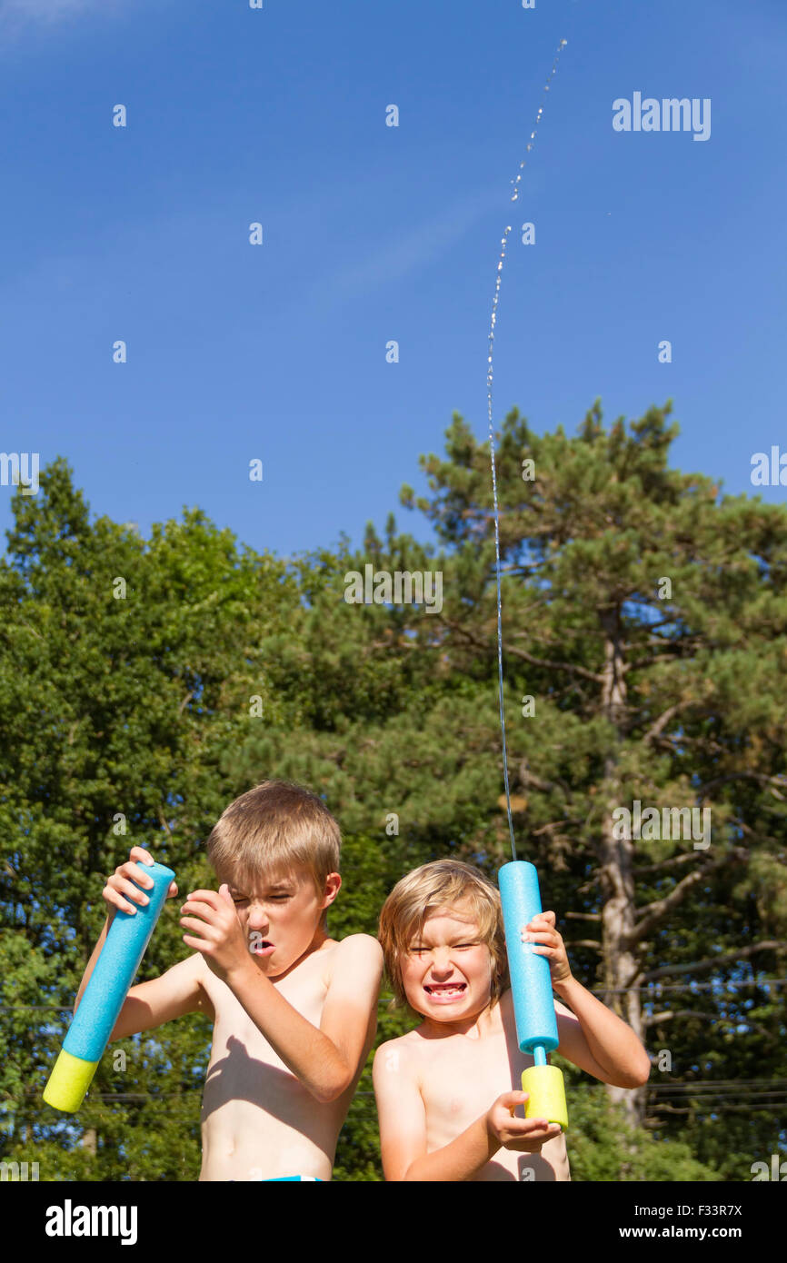 Two young boys outdoors playing with squirt toys. Stock Photo