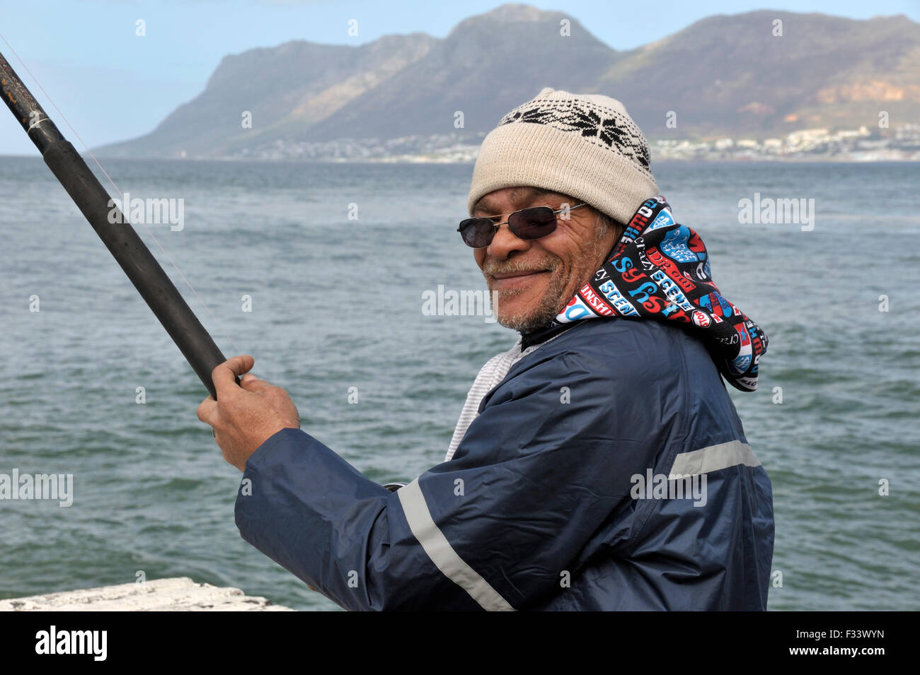 Man fishing off Kalk Bay harbour wall Stock Photo