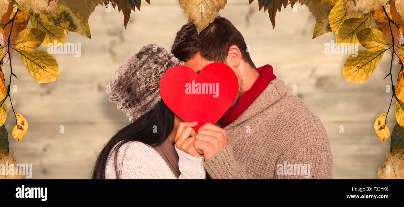 Composite image of young couple kissing behind red heart Stock Photo ...