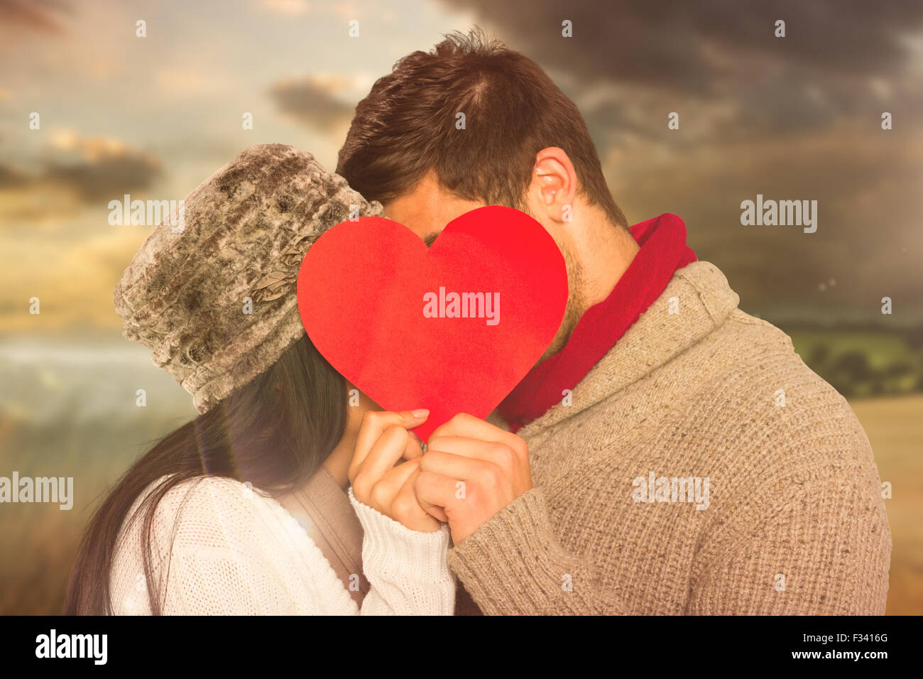 Composite image of young couple kissing behind red heart Stock Photo ...