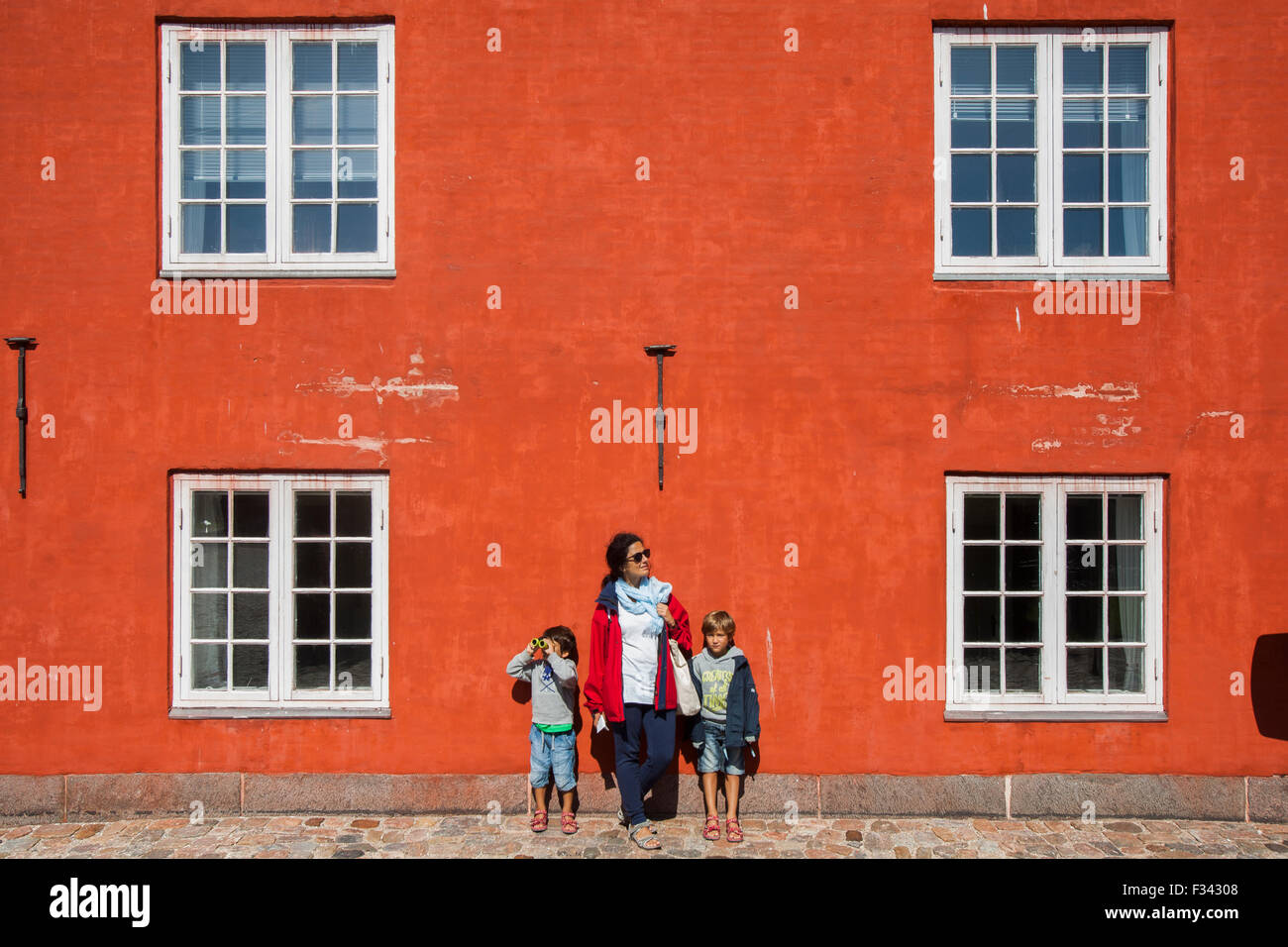 Copenhagen, Denmark -18 Aug 2015- Mother and two child on a red wall at the Kastellet military fotification. Stock Photo