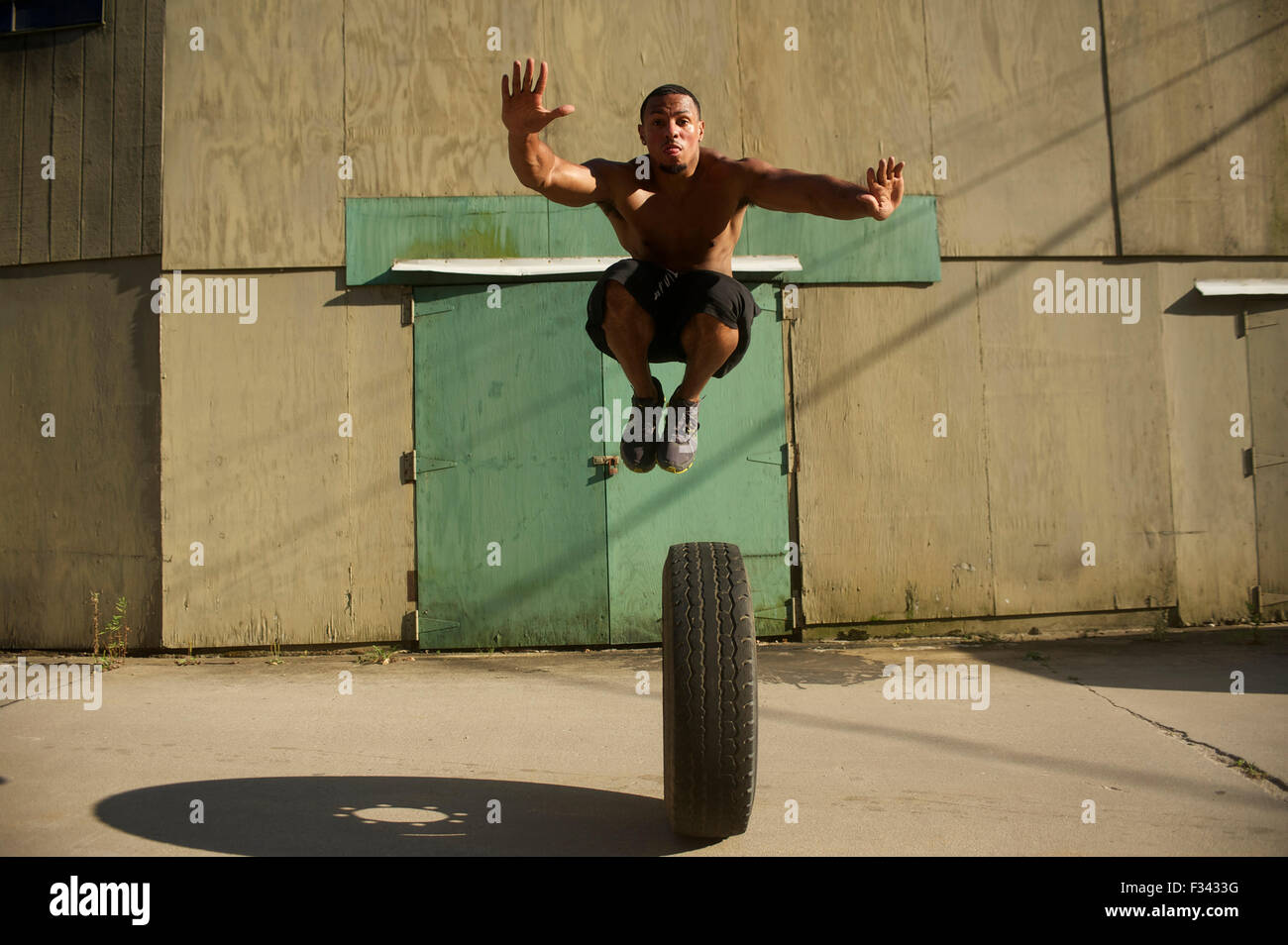 The Five Foot Dunker jumps over a large truck tire to show off his skills. Stock Photo