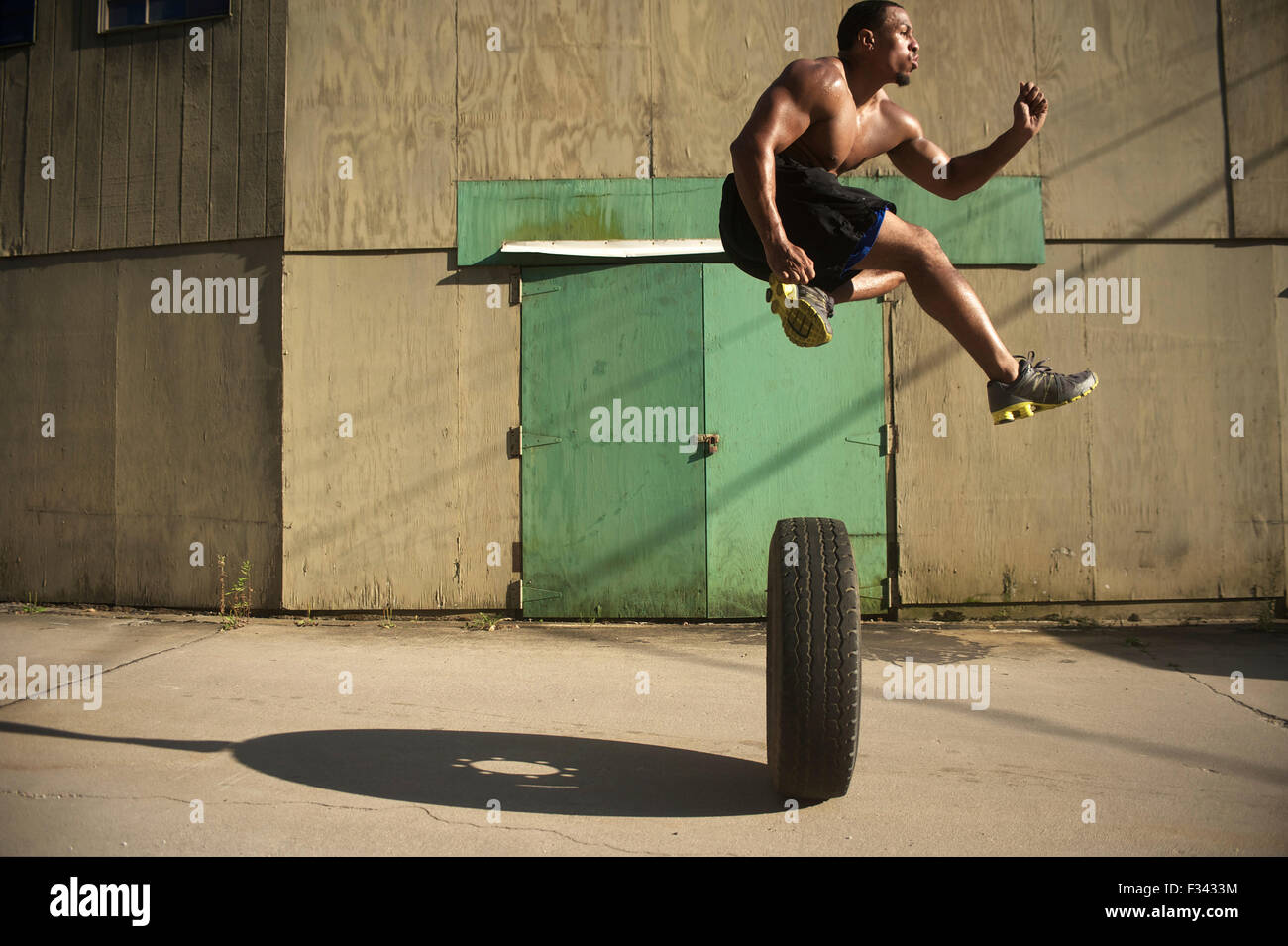 The Five Foot Dunker jumps over a large truck tire to show off his skills. Stock Photo