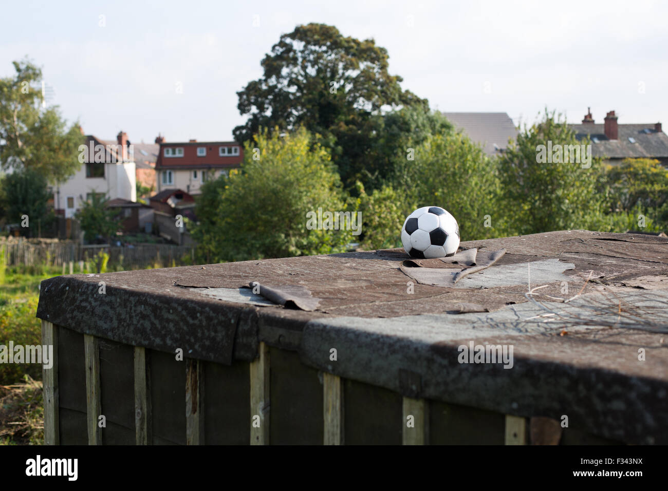 A lost football sits atop a garage roof in the sunshine.   Ian Hinchliffe / ianrichardhinchliffe.co.uk Stock Photo