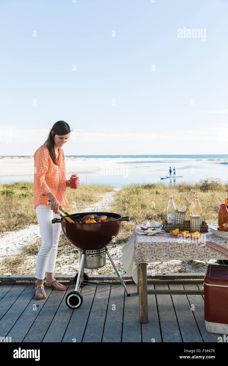 Woman grilling on the beach Stock Photo