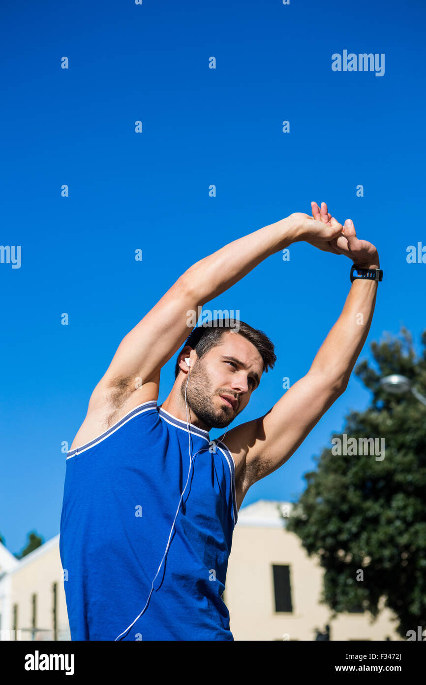 Handsome athlete stretching against blue sky Stock Photo - Alamy