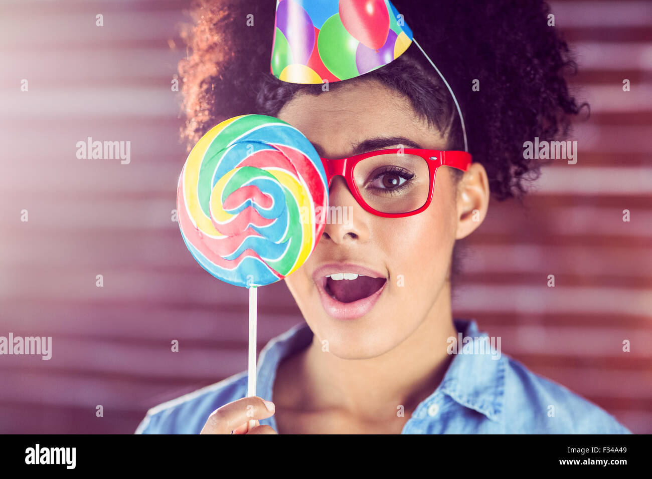 Surprised young woman holding a lollipop against her face Stock Photo
