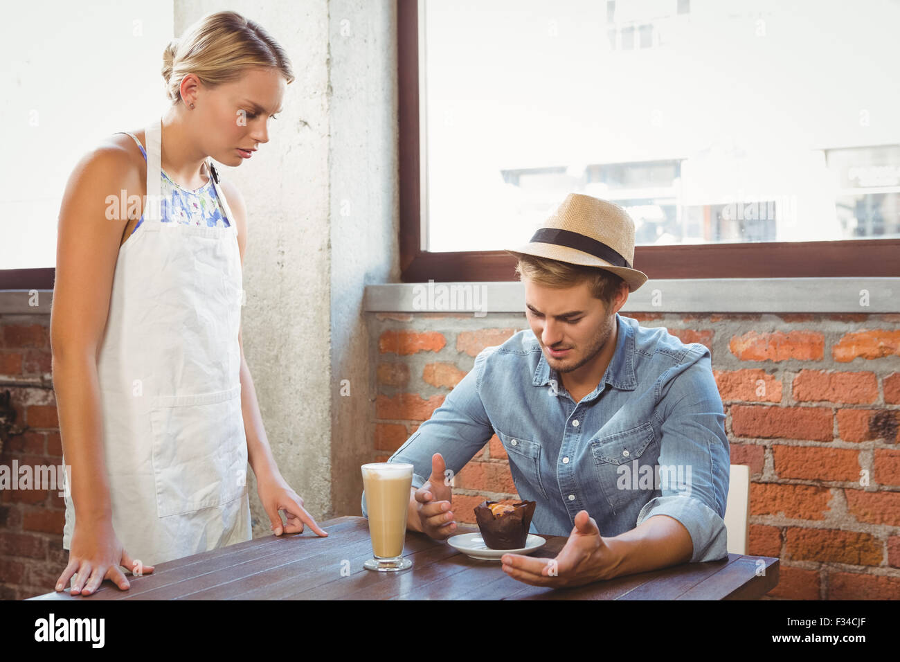 Handsome hipster complaining to blonde waitress Stock Photo