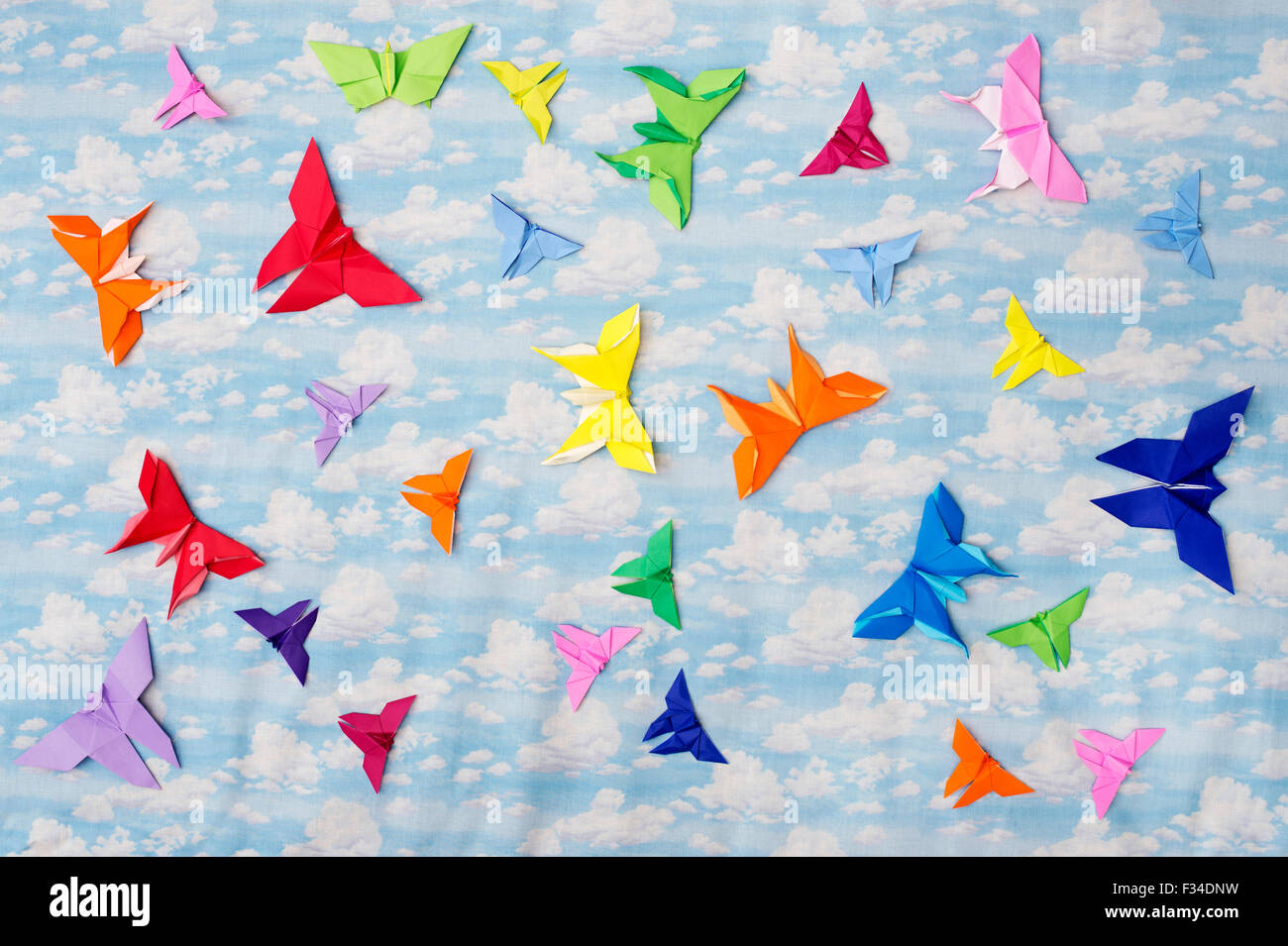 Colourful Origami paper butterflies on a cloudy sky pattern background Stock Photo