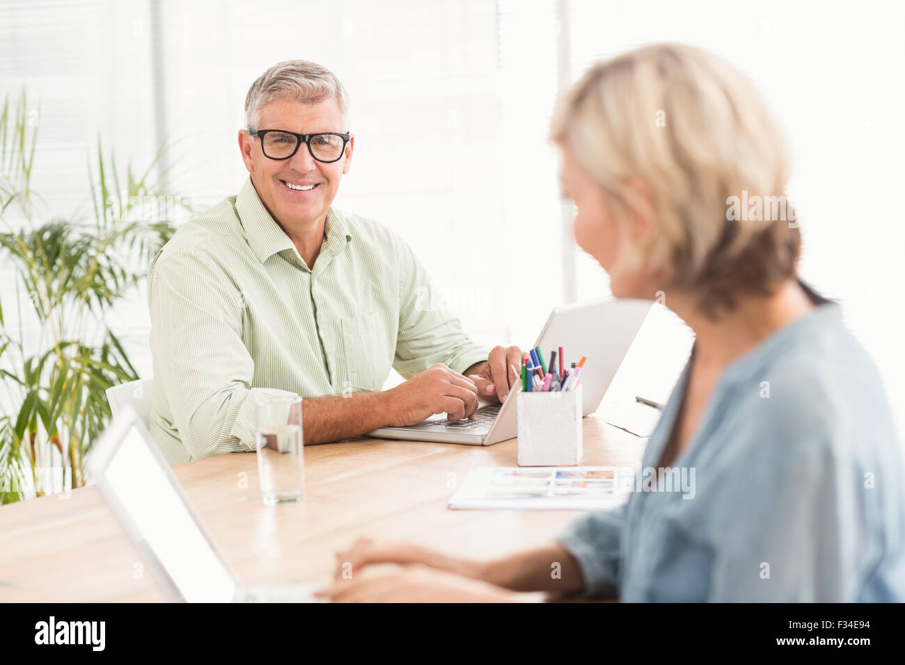 Smiling business team working on laptops Stock Photo - Alamy
