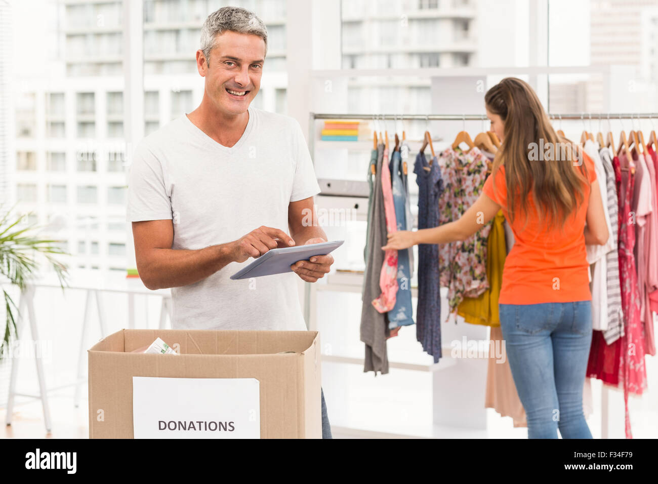 Casual businessman with donation box and tablet Stock Photo